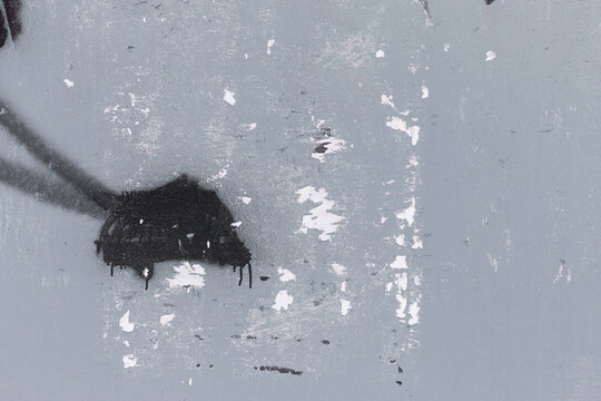 Front view of a messy and weathered urban wall painted in gray with black spray paint and torn posters. Abstract high resolution full frame distressed texture background.