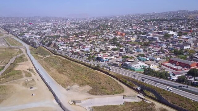 Aerial view of urban landscape and highway near international border wall.