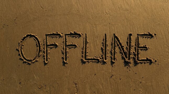 The word 'offline' is written in sand on a sunlit beach, casting shadows.