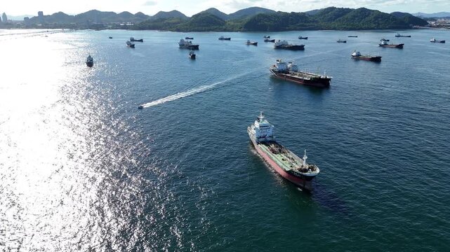 fast patrol boat with LPG gas and oil tanker ships anchored in the ocean, with a fast patrol boat in the foreground. Global energy transport, war energy crisis, and Strait of Hormuz blockade concept