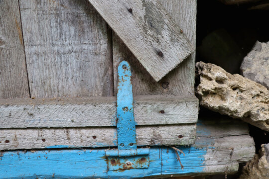 Weathered blue hinge on wooden barn door