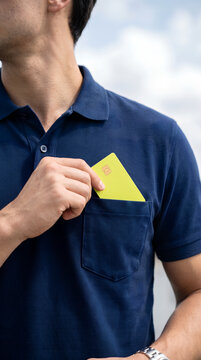 Man tucking yellow card into shirt pocket outside