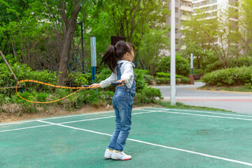 Happy Asian girl skipping rope outdoors in park, active child exercising and healthy lifestyle concept © Li Liu