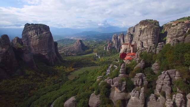 Aerial drone footage of ancient orthodox monasteries perched on top of high rocky sandstone pillars in Meteora valley Greece.
