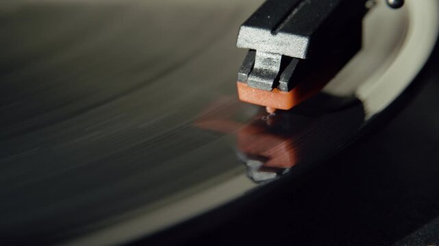 Detailed macro shot of a stylus on a spinning black vinyl record illuminated by natural sunlight. The footage captures analog sound, vintage technology, warm lighting, and nostalgic music culture.