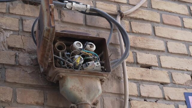 4K 60fps Close-up view of old electrical meter and cables mounted on a brick wall, urban utility infrastructure and residential energy equipment detail