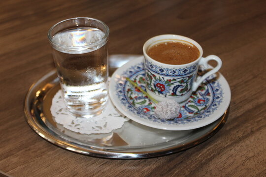 Turkish espresso in a small cup with a glass of water.