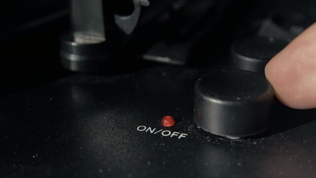 Close up shot of a finger pressing the on off power button of a vintage vinyl record player