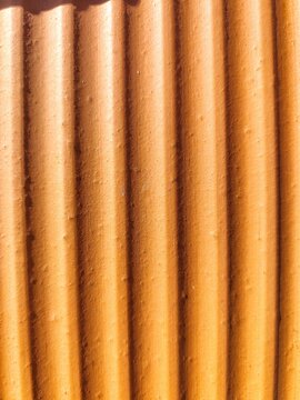 Angled close up of orange terracotta roof tile waves with curved shadows
