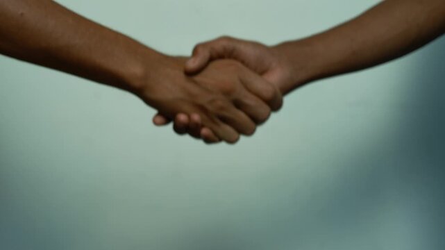 Handshake Showing Trust and Partnership, Close-up of two people shaking hands against a soft blurred blue background, showing agreement, trust, partnership and business connection.