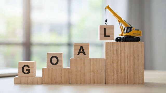 Miniature crane building the word goal with blocks