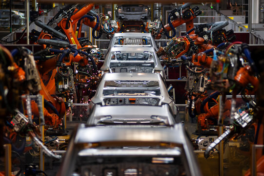 Automated production line for the automotive industry; intelligent factory robotic arms in a vehicle manufacturing workshop.