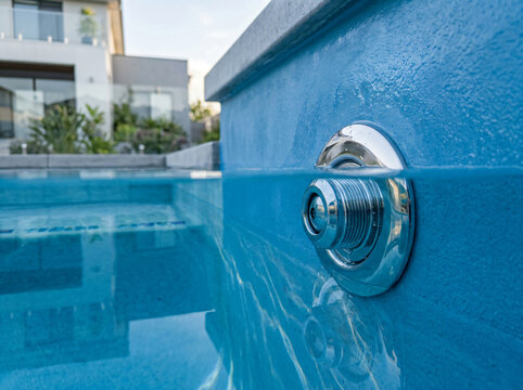 Modern swimming pool jet underwater view | Residential pool maintenance and cleaning | Close-up of pool water return nozzle | Backyard pool equipment and filtration | Blue water surface split shot