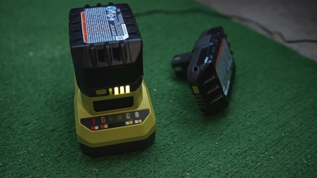 Power tool battery charging on charger with charge level indicator showing charging process and battery status on working surface
