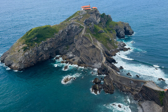 serene island chapel with rocky cliffs and stairs leading to ocean, aerial view, green and blue tones, stationary scene, travel, architecture, nature, clean, background, copy space, design.
