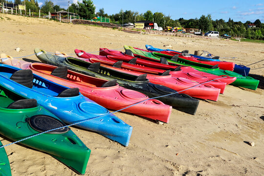 MUCHARZ, POLAND - SEPTEMBER 06, 2026: Plastic pedal boats, kayaks, and rowboats pulled up onto the sandy lake shore after the summer season. End of tourist season, quiet beach, off-season stillness