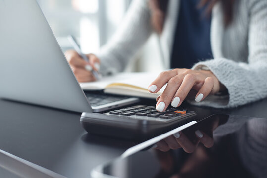 Close up, business woman working at office, using calculator to calculate company finance, accounting with laptop on desk, doing finance, budgeting and tax calculation