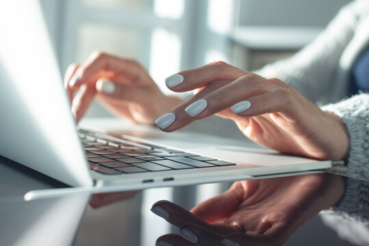 Closeup, Business woman hand typing on laptop keyboard with reflection on glass table at office. Internet networking, online working concept