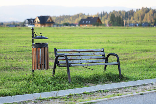 A lonely, empty wooden bench set against a lush green meadow. A deep metaphor for solitude, emptiness, contemplation, longing, and peace in nature.