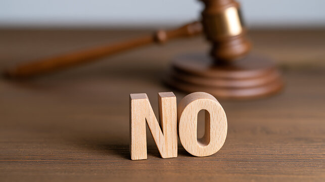 Wooden gavel and the word no in wooden block letters on a desk, representing legal rejection, court decision, verdict, and denial concept