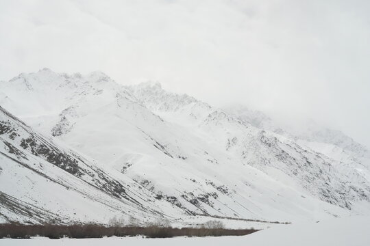 Snow covered mountain range under a cloudy sky in winter