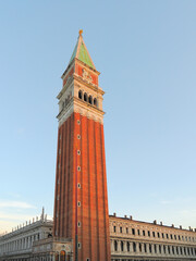 The iconic Campanile bell tower rising above Piazza San Marco against a clear blue sky in sunset colors, Venice, Italy © Konstantinos
