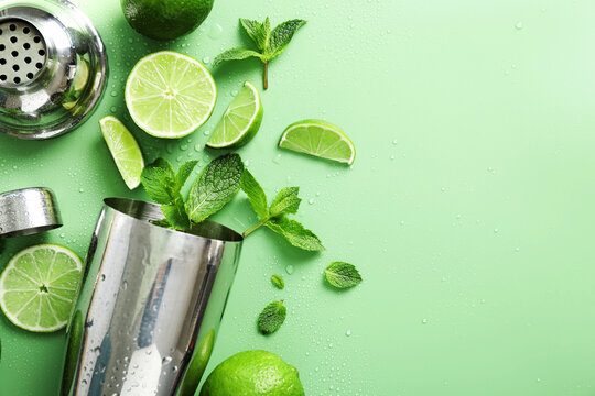 Shaker, limes and mint on green background, flat lay. Space for text