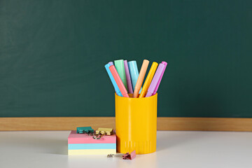 Stationery on white table against chalkboard. Space for text