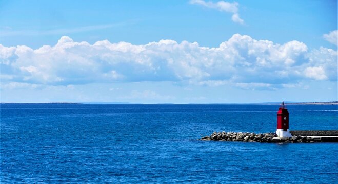 Red lighthouse on the sea with clouds and beautiful blue horizon, seascape scene with lighthouse