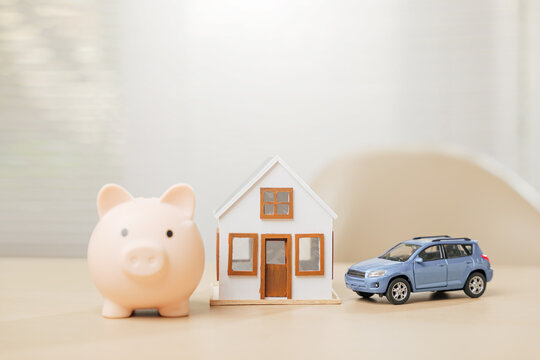Piggy bank with house and blue car models symbolizes saving money for a dream home and auto. Highlights property investment, asset building, and expense management with finance