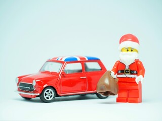 Obraz premium Indonesia - September 11, 2023 : Mini toy at table with blurred background. Oldman Santa Claus carrying gift concept design.