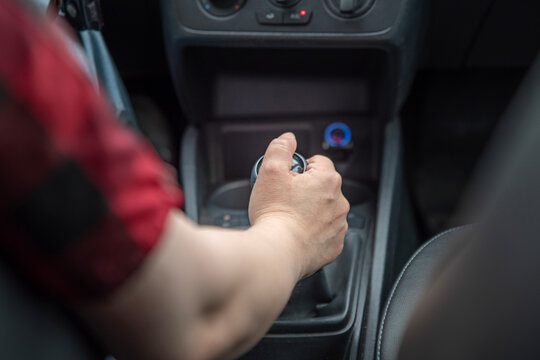 Close-up of a driver&rsquo;s hand operating a manual gear shift inside a car. Manual transmission, vehicle control, driving skills and changing gears concept.