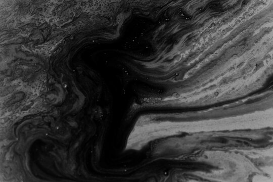 Abstract black liquid surface covered with small bubbles and swirling foam, resembling oil pollution or a chemical spill.