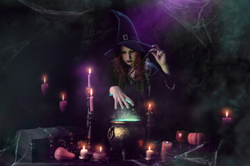 Witch with magic wand casts spell, witch's cauldron, boiling magic potion, room with candles. Young woman witchcrafting, magician girl with red hair, dressed in Halloween attire and conical hat © TSViPhoto