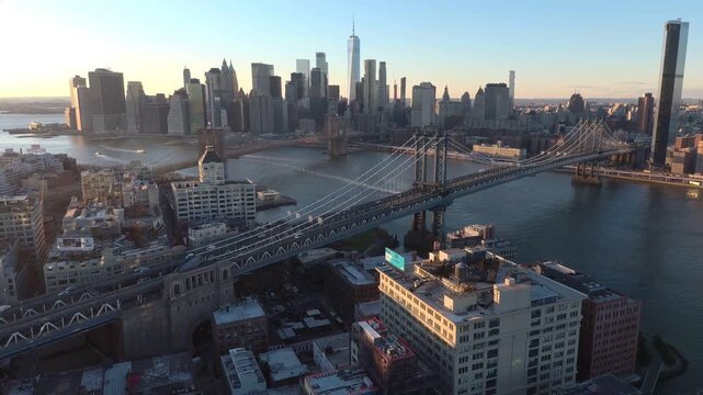 Cinematic aerial view of Manhattan bridge and New York City skyline at golden hour.