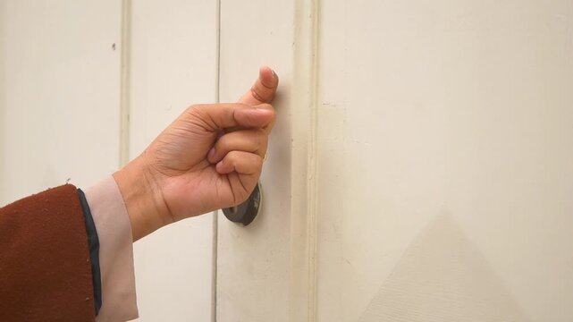 Close up hand knocking on white door in slow motion video clip