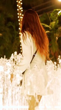 Smiling woman enjoying an illuminated fountain at night in West Palm Beach