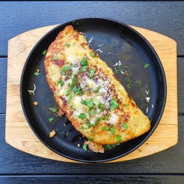 Huge traditional Belarusian potato pancake draniki filling entire cast iron frying pan rustic homemade food, close golden crispy texture.