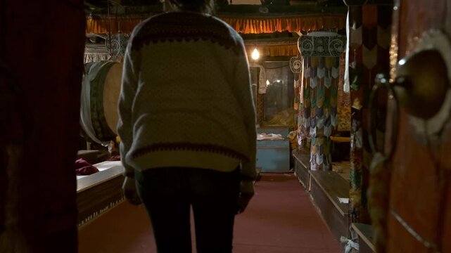 Woman exploring the historic Key Monastery in Spiti Valley, Himachal Pradesh, India, walking through its traditional Buddhist interior with colorful Tibetan decorations.