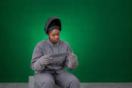 Woman welding student inspecting a weld on a steel bracket in a workshop