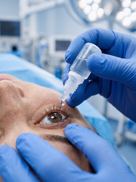 close-up of gloved hand applying liquid eye drops into a patient's eye during an ophthalmology procedure in a clinic