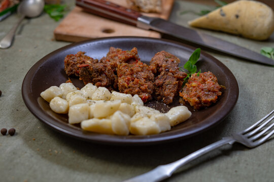 Traditional potato gnocchi served with slow cooked meat stew and vegetables on dark plate