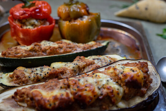 Baked stuffed peppers and zucchini with minced meat, cheese and herbs on rustic plate