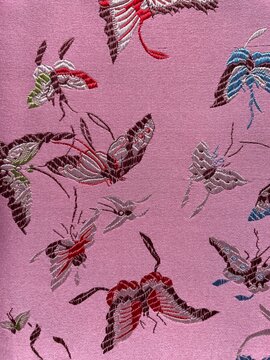 Pink textile featuring intricate butterfly motifs in multiple color