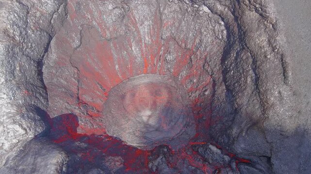 Aerial view of active volcano crater with molten lava bubbling and glowing in rocky pit.