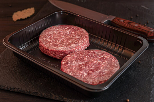 Raw minced meat patties for burgers prepared for cooking on dark board