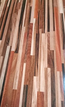 Close up of multi color wooden floor texture with mixed parquet planks. Natural laminate flooring with brown, beige, red and dark wood pattern.