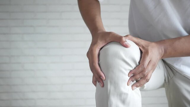 Man holding painful knee experiencing discomfort and injury