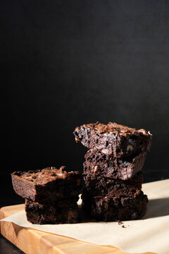 Triple chocolate brownies in a stack on a dark surface 