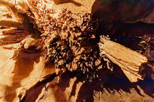 Tight group of stalactites and calcite protrusions diverging from a rock pillar, Pyrenees, France